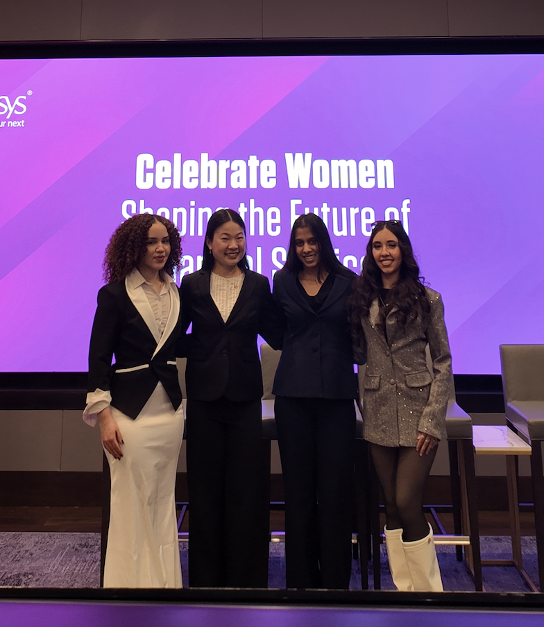 Four women on stage celebrating together at a community event